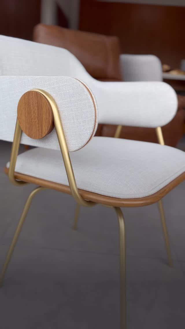 Poltrona de design com estrutura dourada, madeira e tecido claro